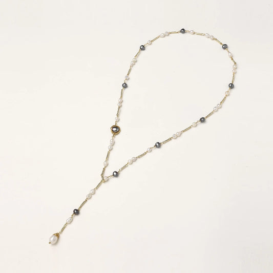 Y-shaped gold-plated necklace with white and gray freshwater pearls on cream background, showing adjustable drop design.