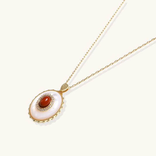 Gold pendant with oval mother-of-pearl frame, amber stone center, and crystal halo on delicate chain