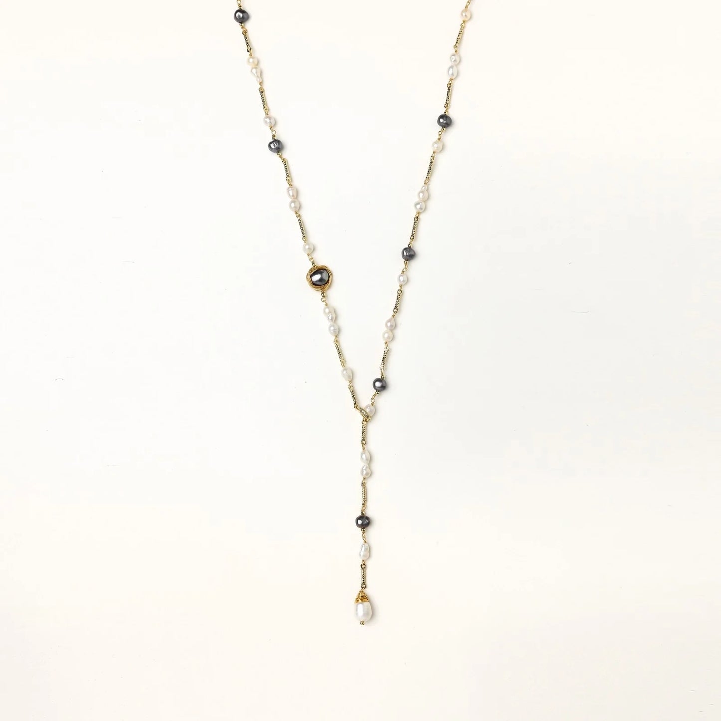 Y-shaped gold-plated necklace with white and gray freshwater pearls on cream background, showing adjustable drop design.